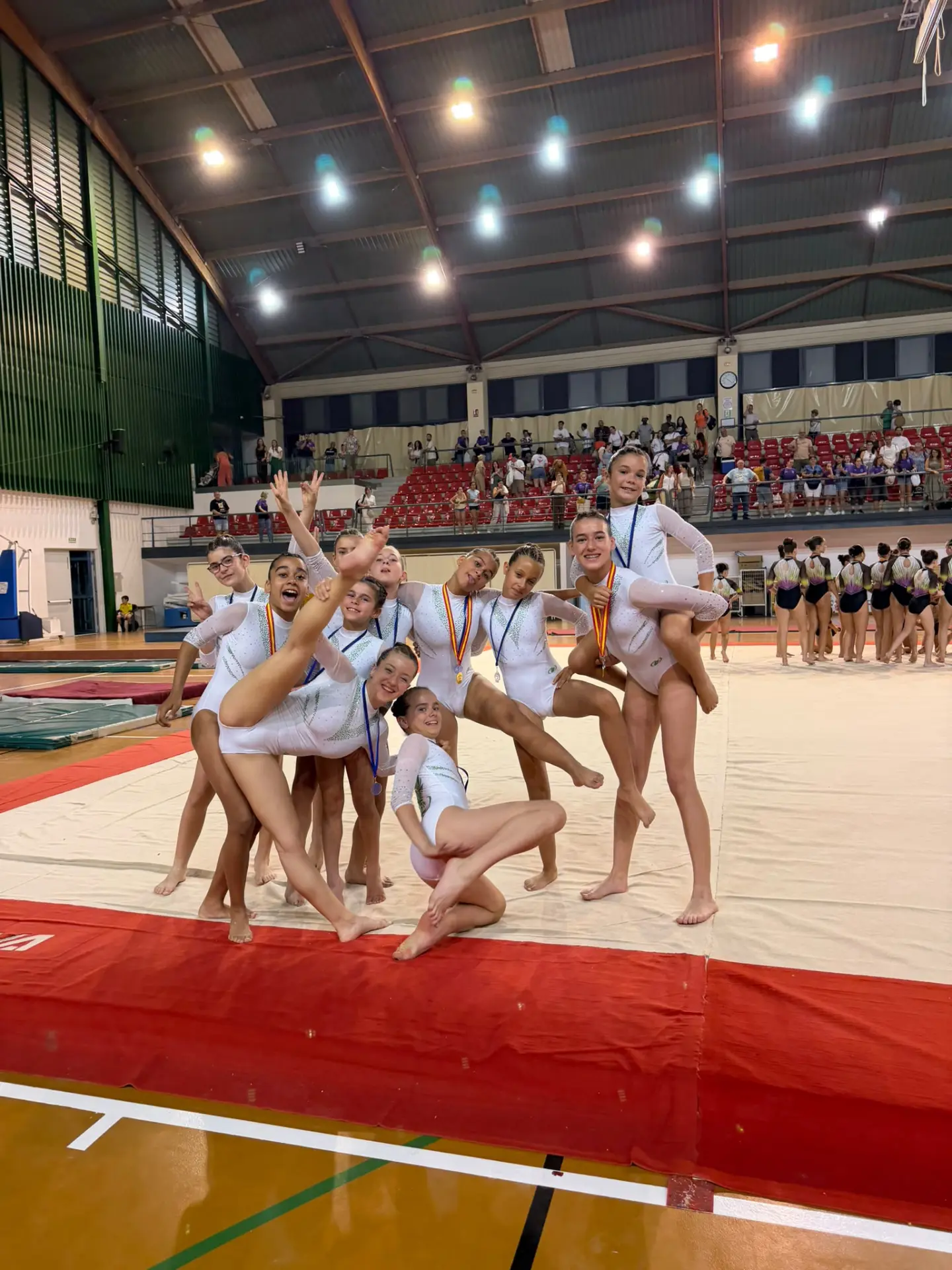 Equipo del Club Fénix Las Rozas celebrando con sus medallas en el tapiz de competición